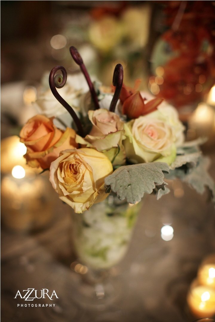 small flower arrangement  of peach roses, dusty miller, fiddlehad ferns in silver mercury vase