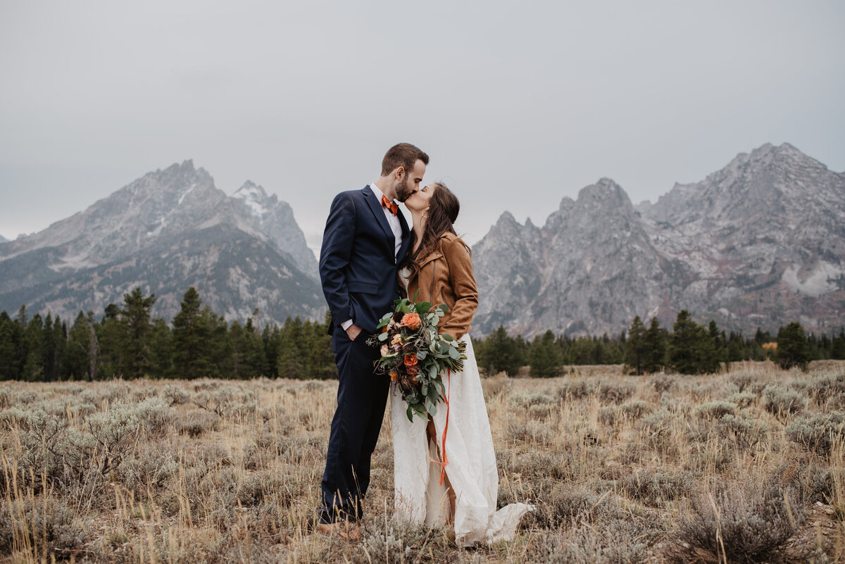 Photographers Jackson Hole capture bride and groom kissing in front of Tetons