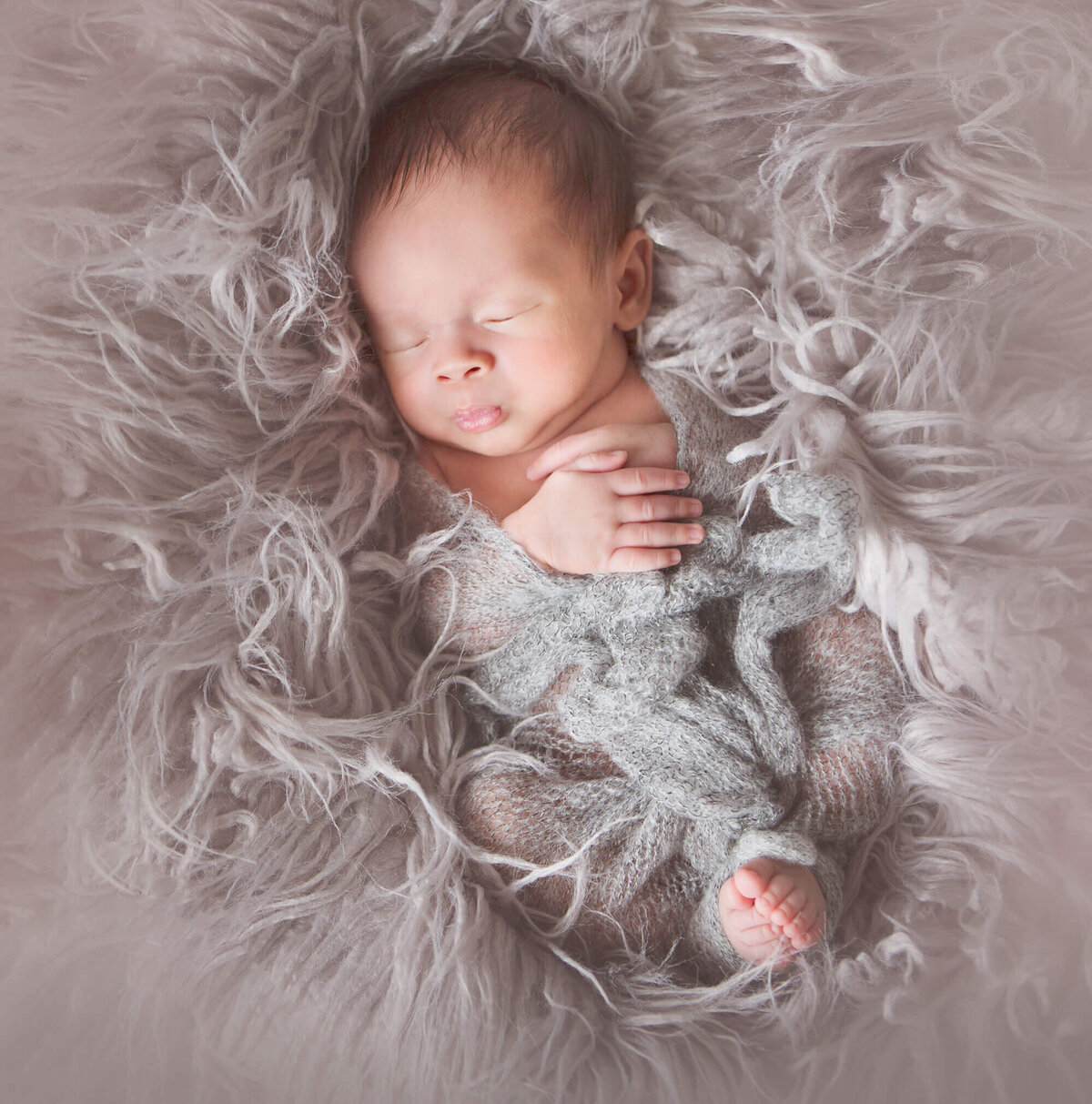 Newborn swaddle laying in grey fur at a newborn photoshoot in LA