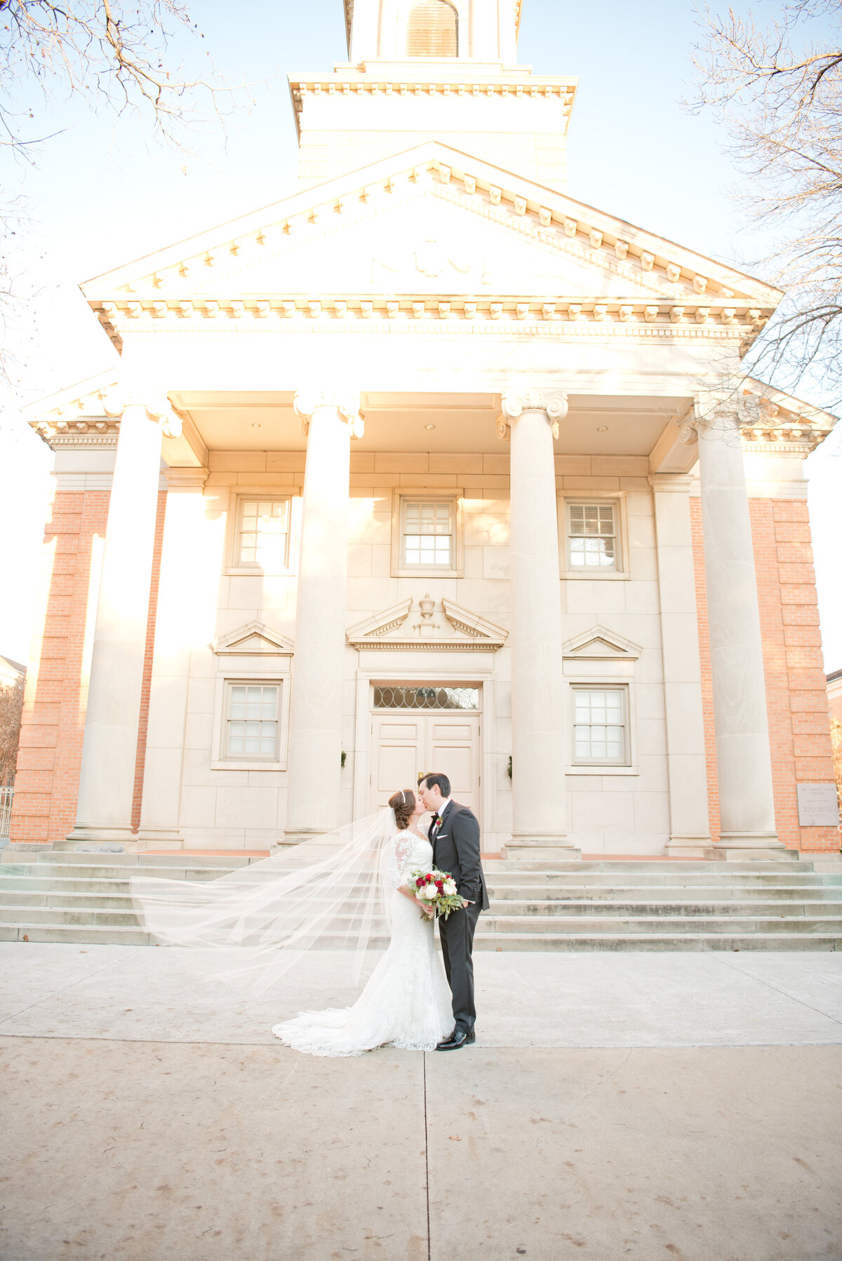 Bride and groom kiss with flowing veil at Robert Carr Chapel in Fort Worth Texas wedding