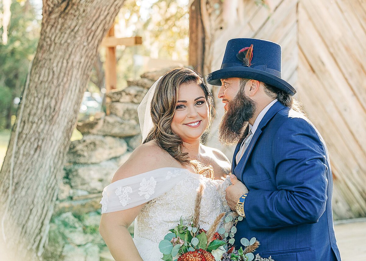 Groom with top hat poses with bride at Bending Branch Ranch