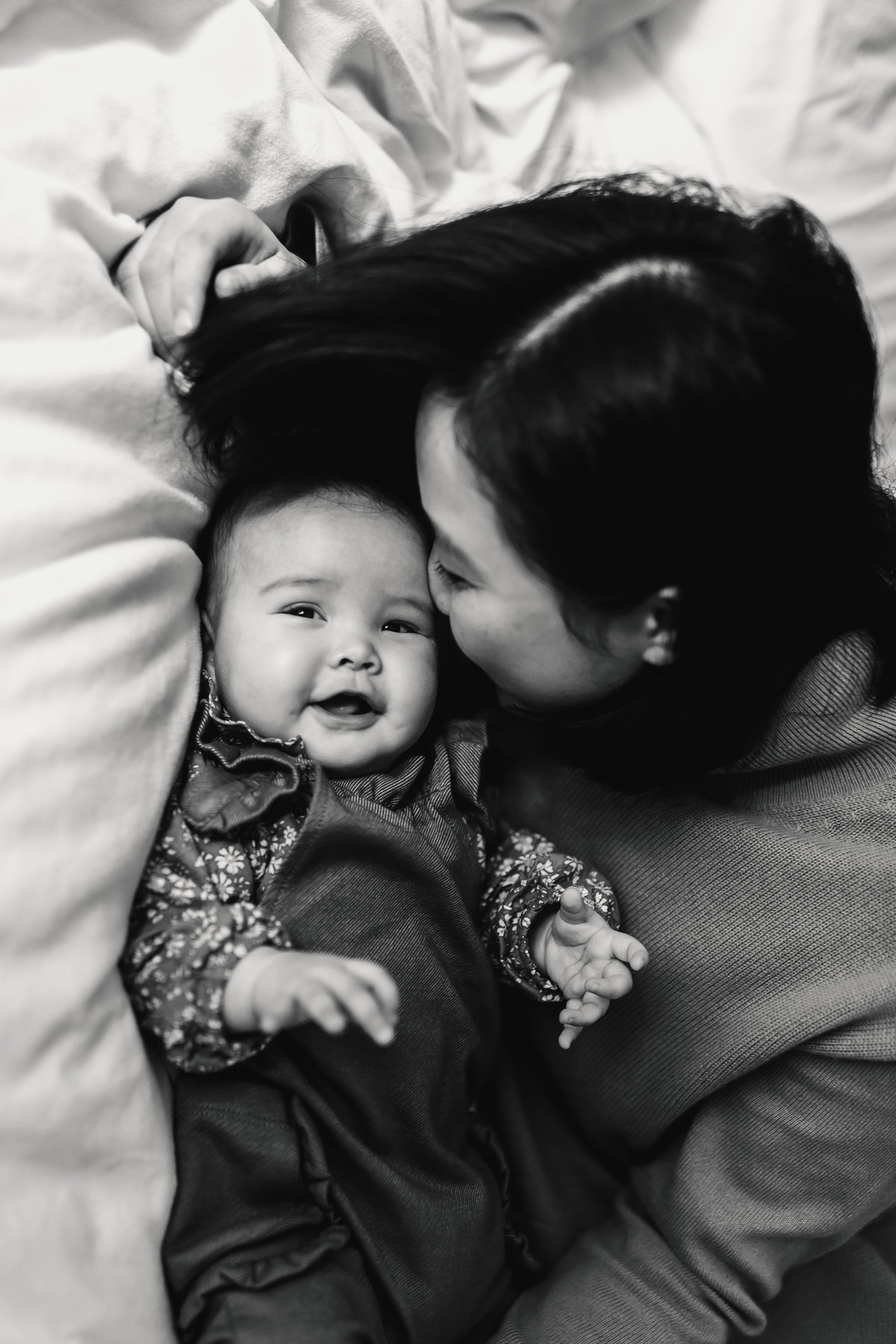 San Francisco mom kisses baby on bed in home family photography session