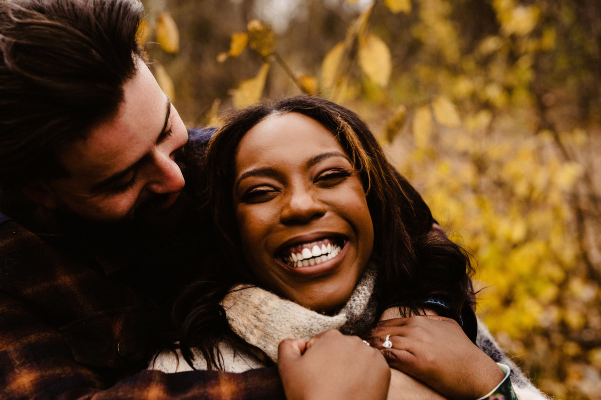 portrait of biracial couple laughing in forest