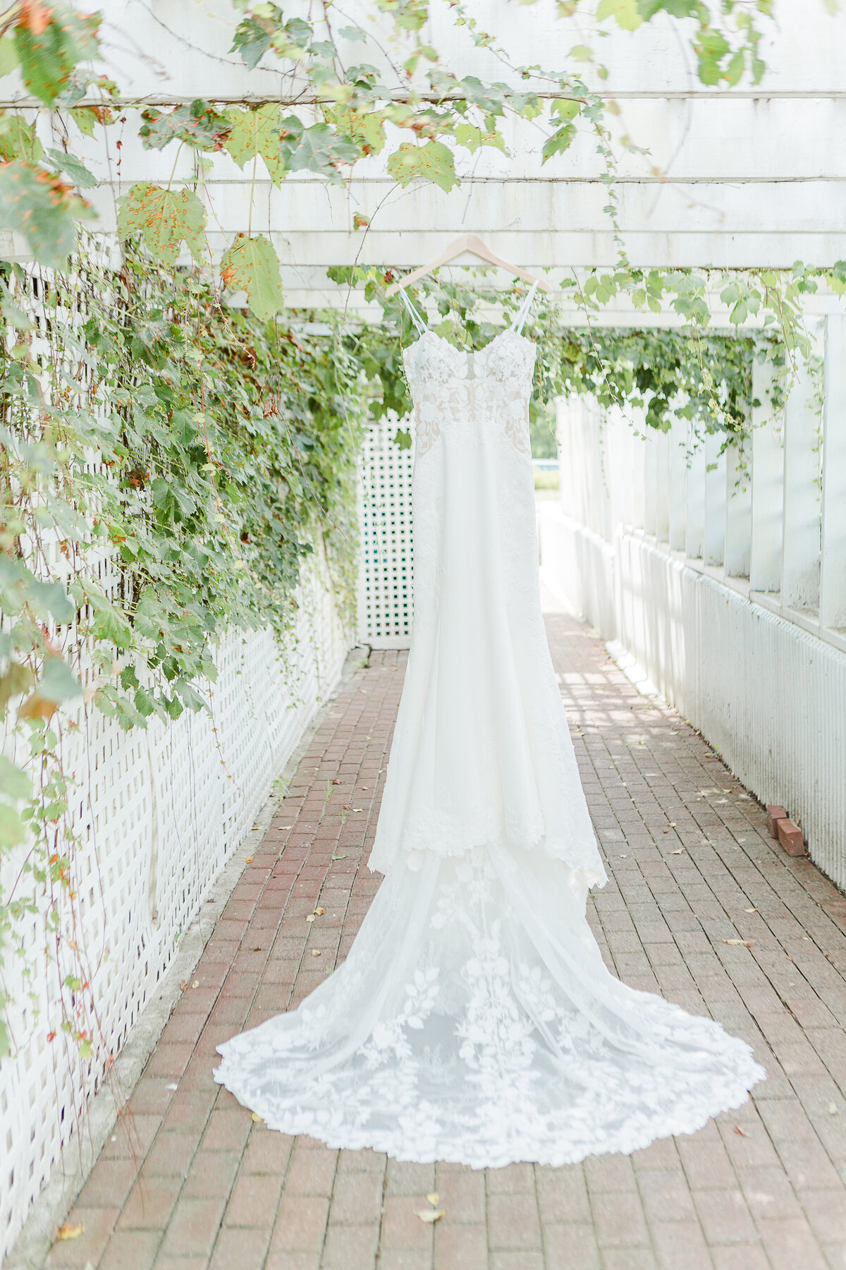Detail image of the bride's wedding dress hanging from the pergola at the Five Bridge Inn. Captured by best Massachusetts wedding photographer Lia Rose Weddings.