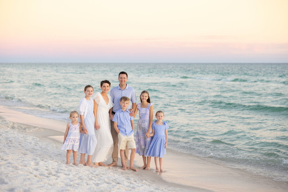 A family smiling and standing at the ocean's edge