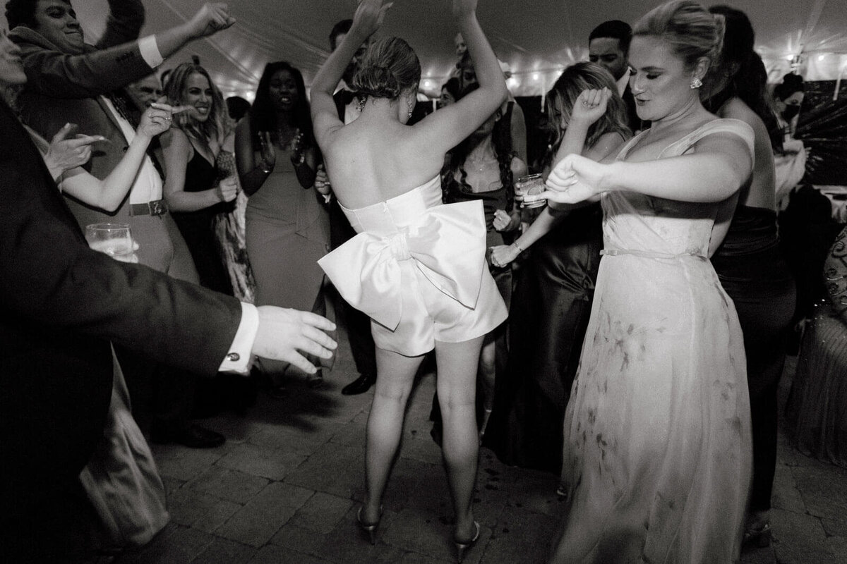 The bride in her bridal romper, happily dancing on the dance floor with the guests at Lion Rock Farm, CT. Image by Jenny Fu Studio