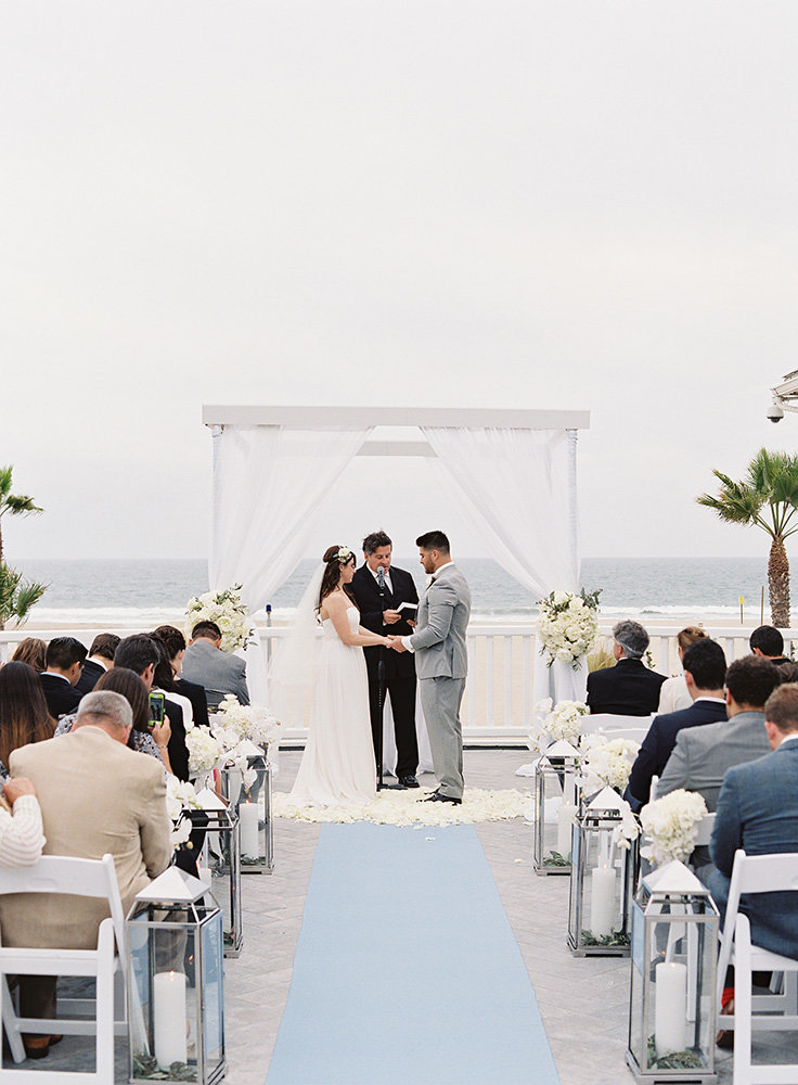 white chuppah with blue aisle runner