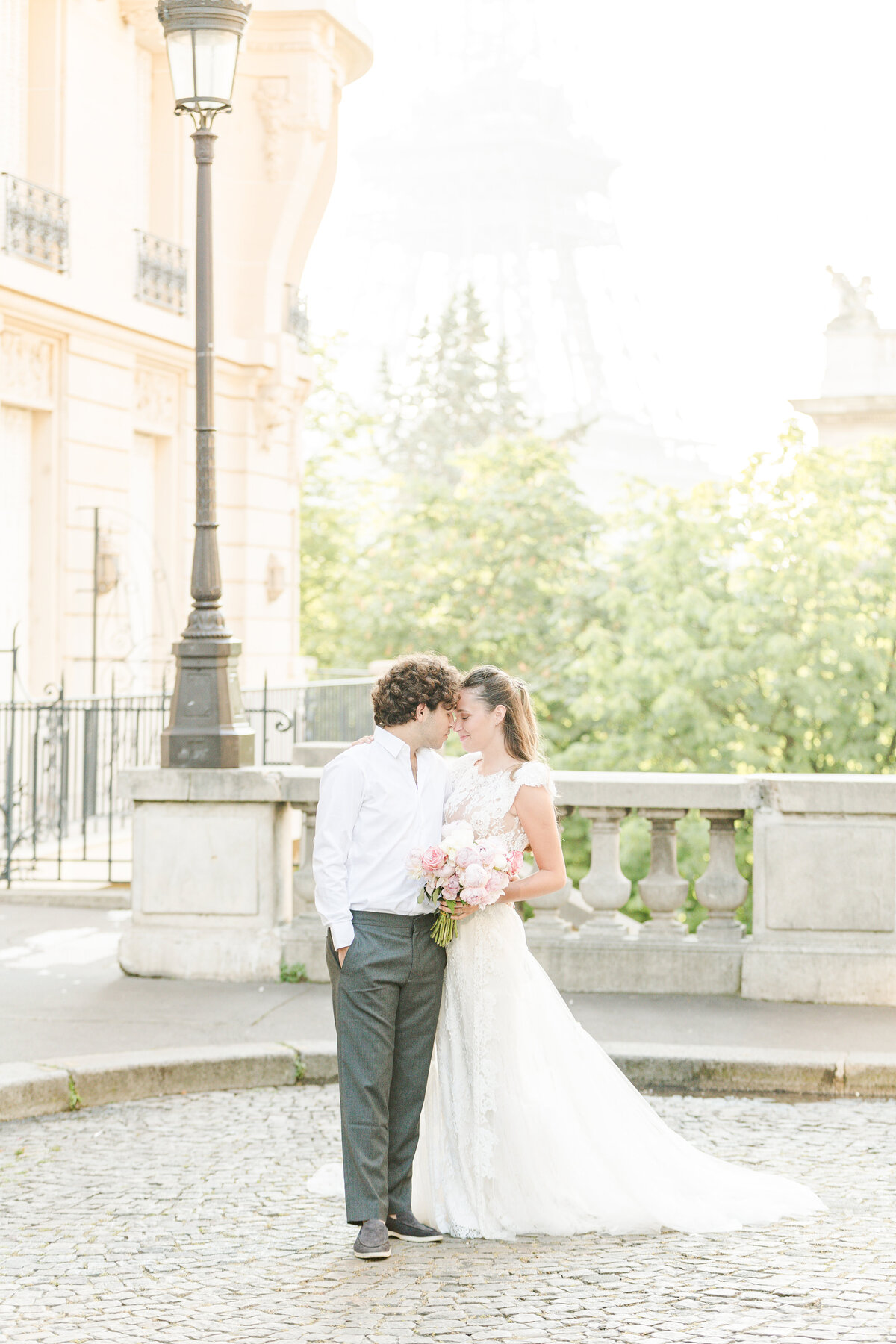 Bride and groom stand on the stone streets of Paris for an intimate wedding photo. Their bodies are pressed together and their foreheads touching. Captured by US-based destination wedding photographer Lia Rose Weddings