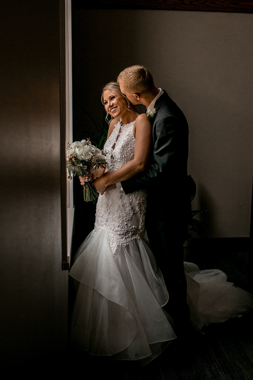 Des Moines Iowa wedding couple cuddling by the window.