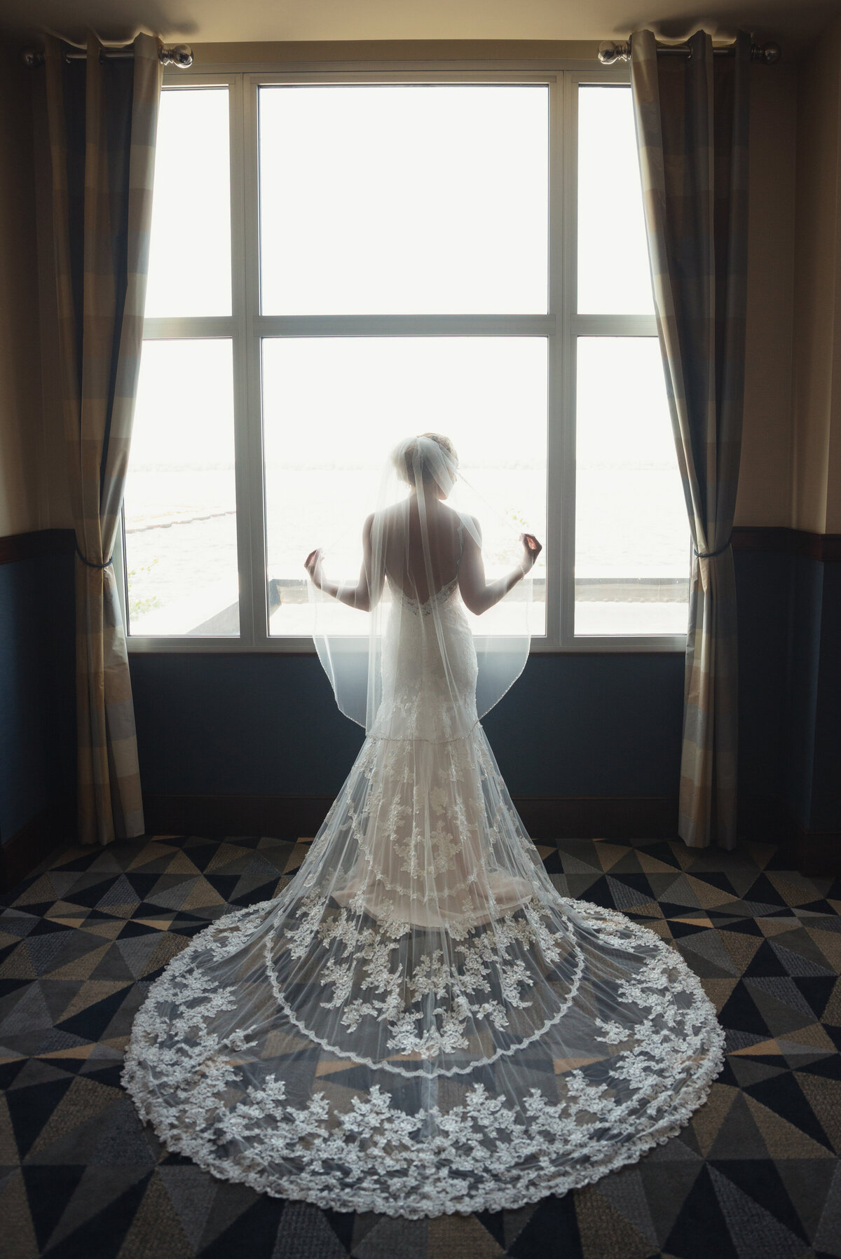 Bride in front of window showing wedding dress.