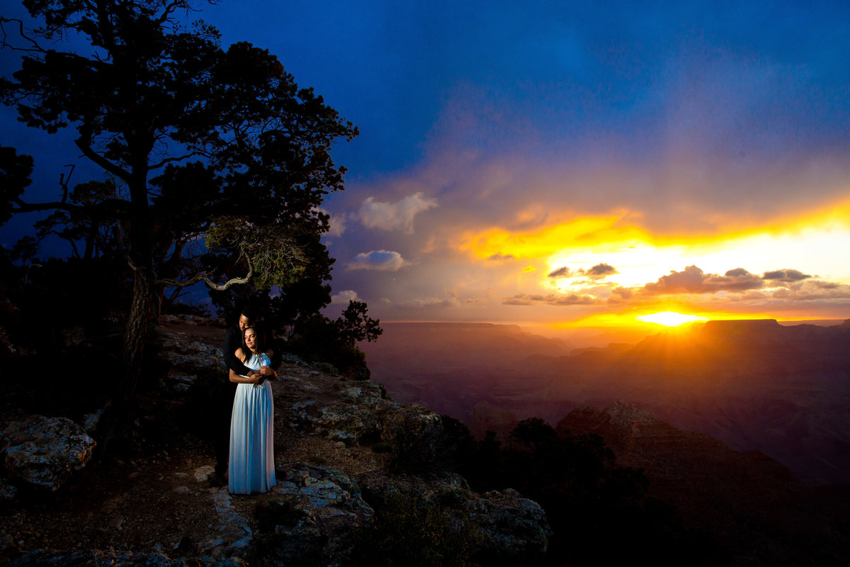 A bride and groom stand on a cliffside.