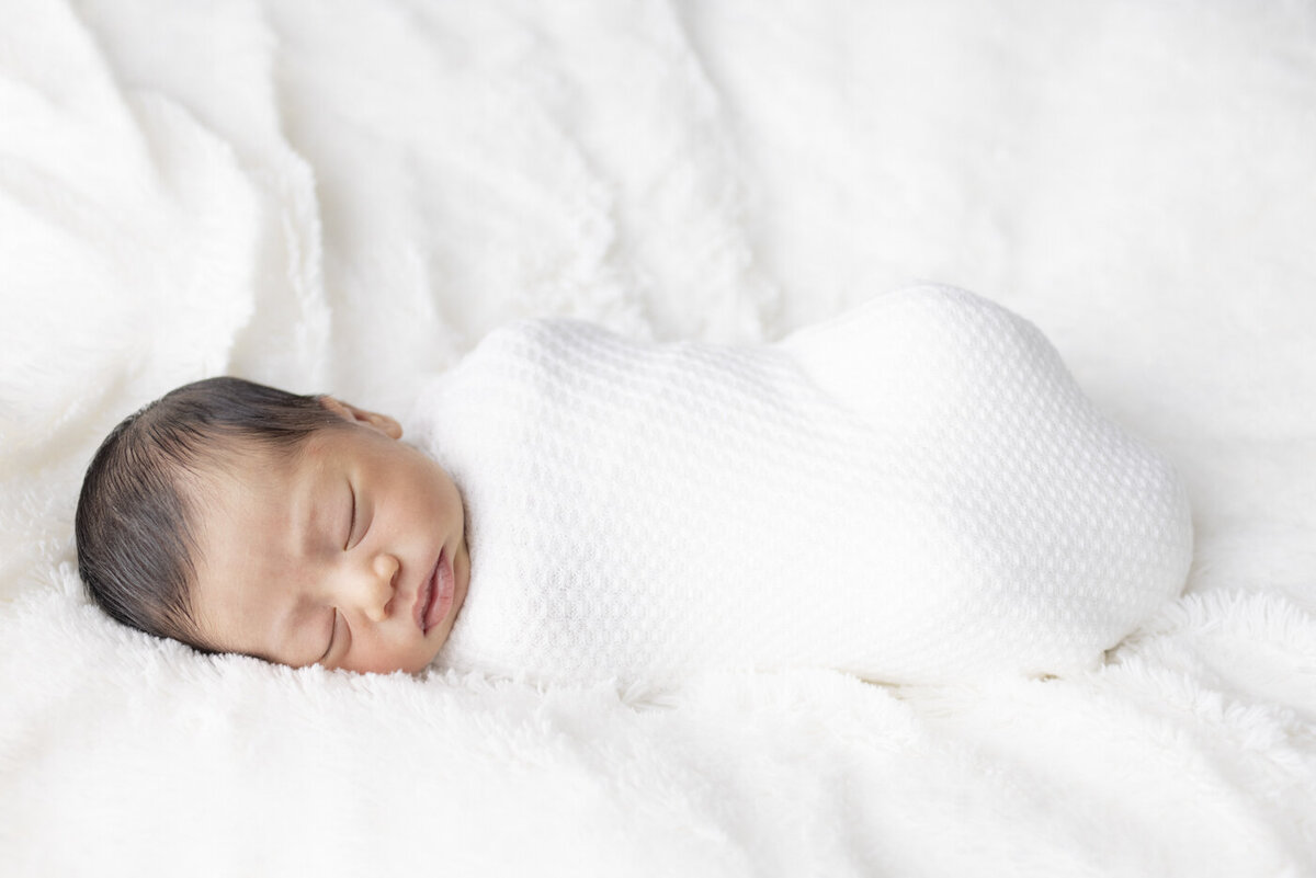 baby boy swaddled in white for newborn portraits