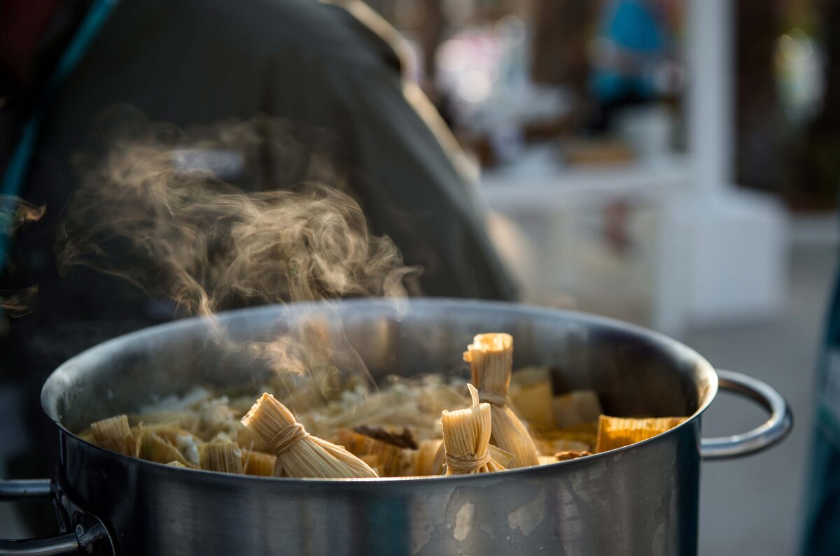 Steam rises from a pot filled with tamales.