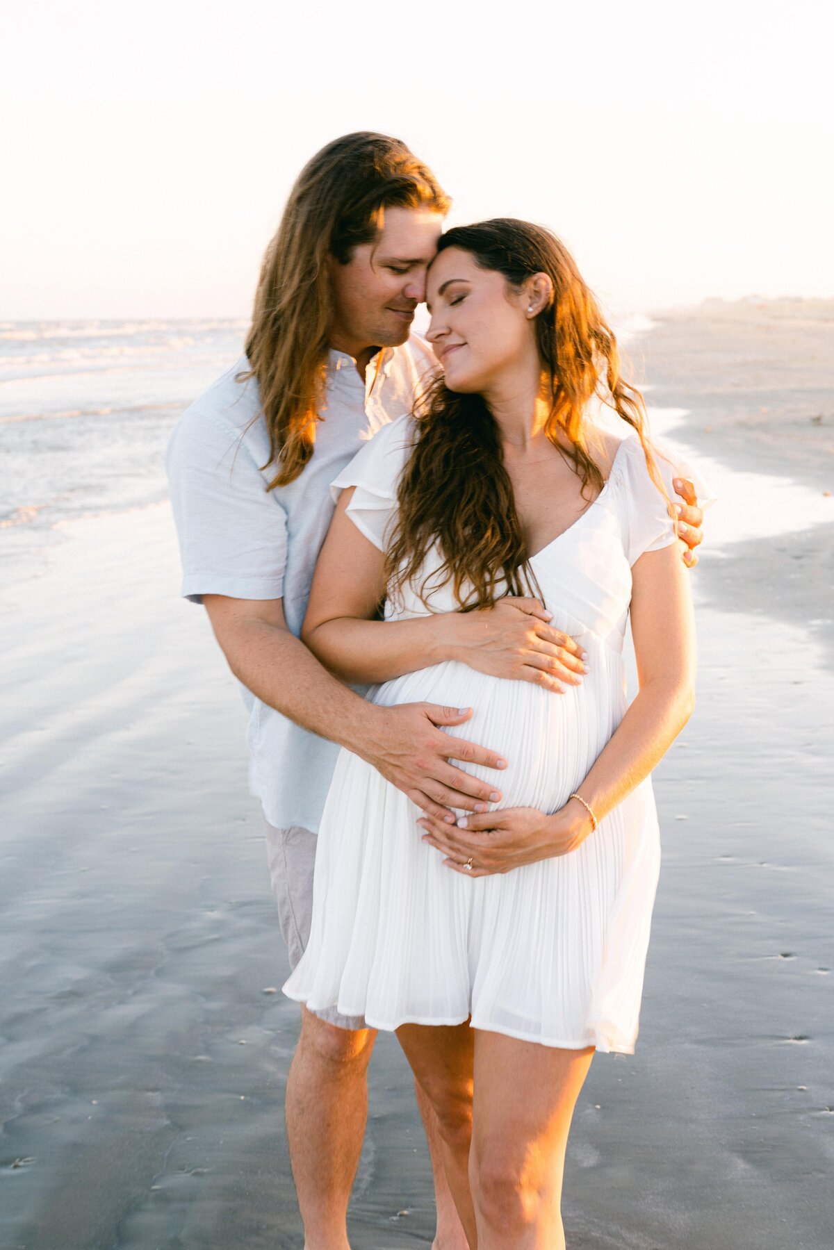 Pregnant couple embracing at the beach