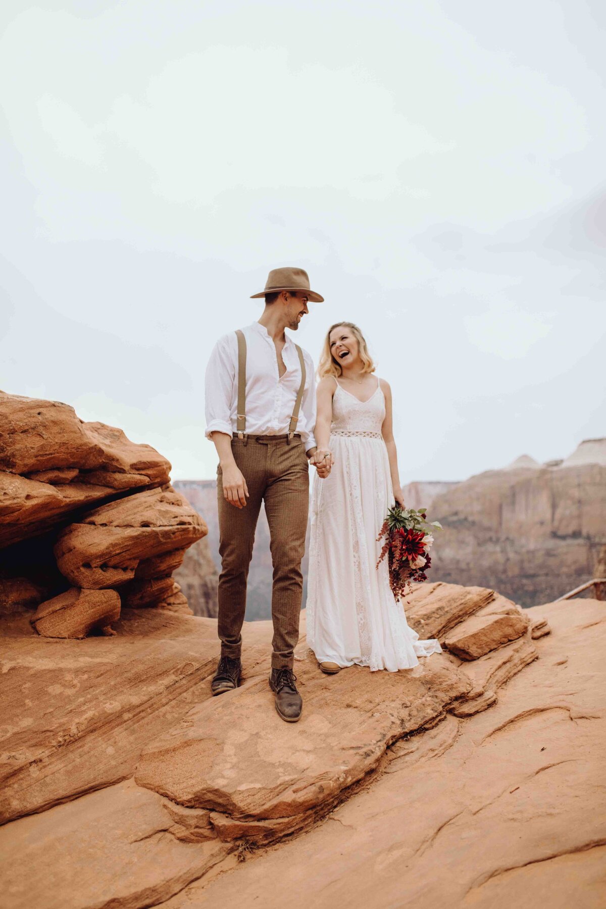 Elopement in Zion National Park. Bride and Groom walking hand in hand, laughing and smiling at each other.