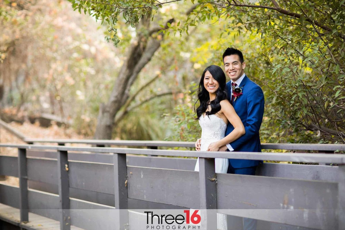 Newly married couple poses for a photo on a bridge