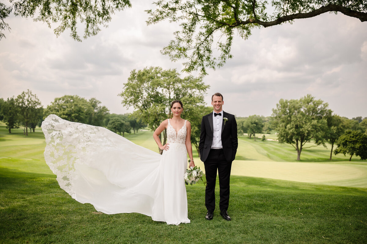 Bride and groom on gold course with flying dress at Biltmore Country Club in Barringhton, IL
