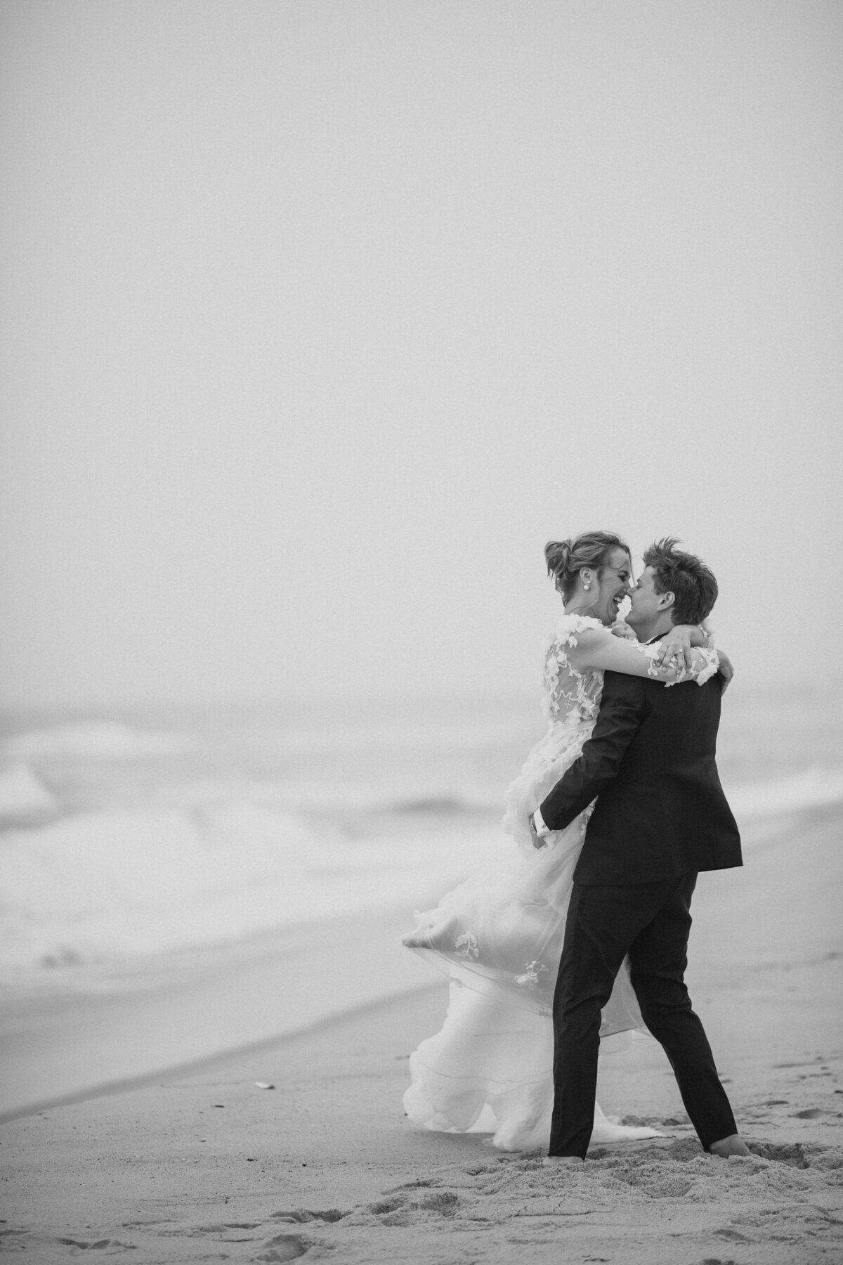 A bride and groom about to kiss on a beach.