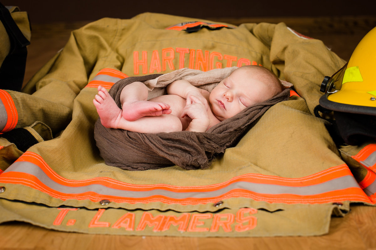 Newborn baby in daddy's fireman gear