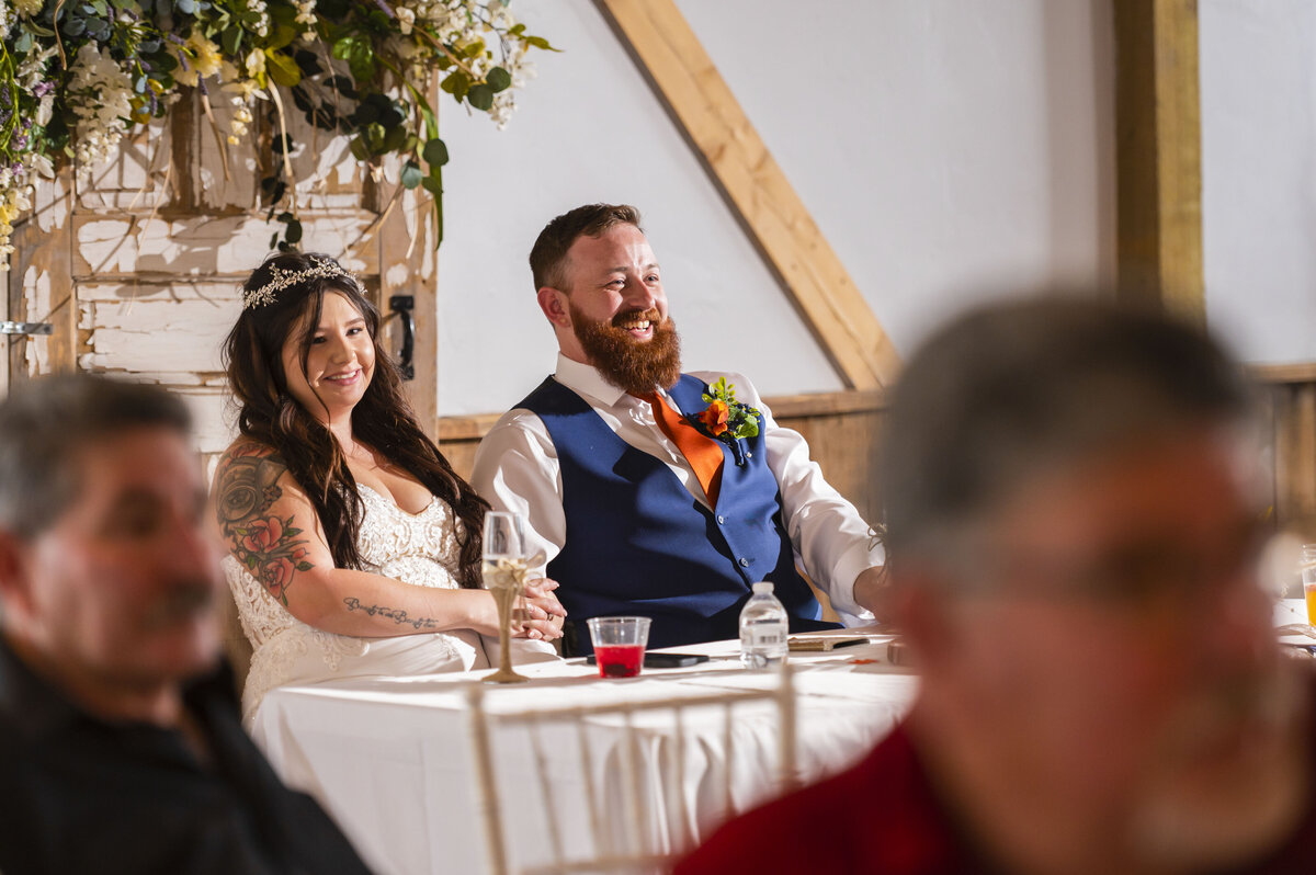 Bride and Groom during best mans speech at reception laughing at his jokes
