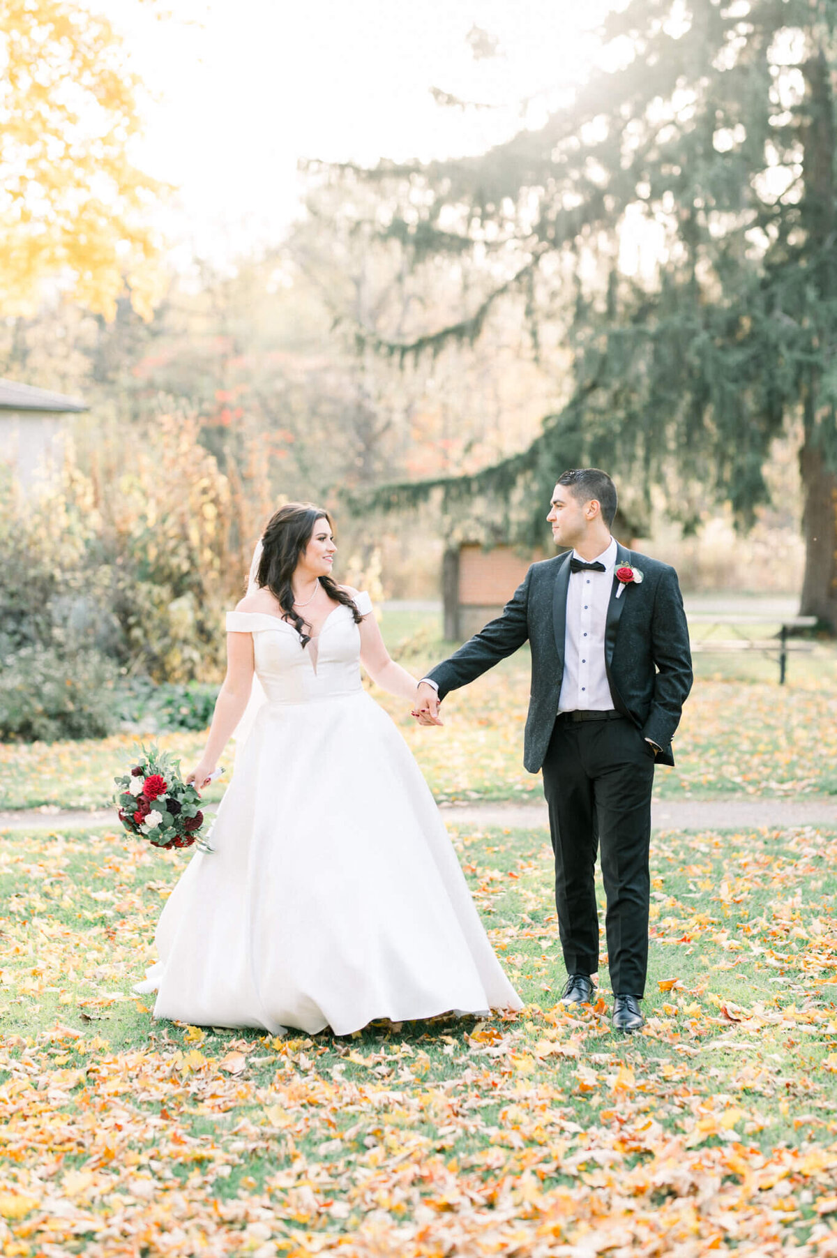 Bride and groom walking holding hands in the Fall. Captured by Niagara wedding photographer
