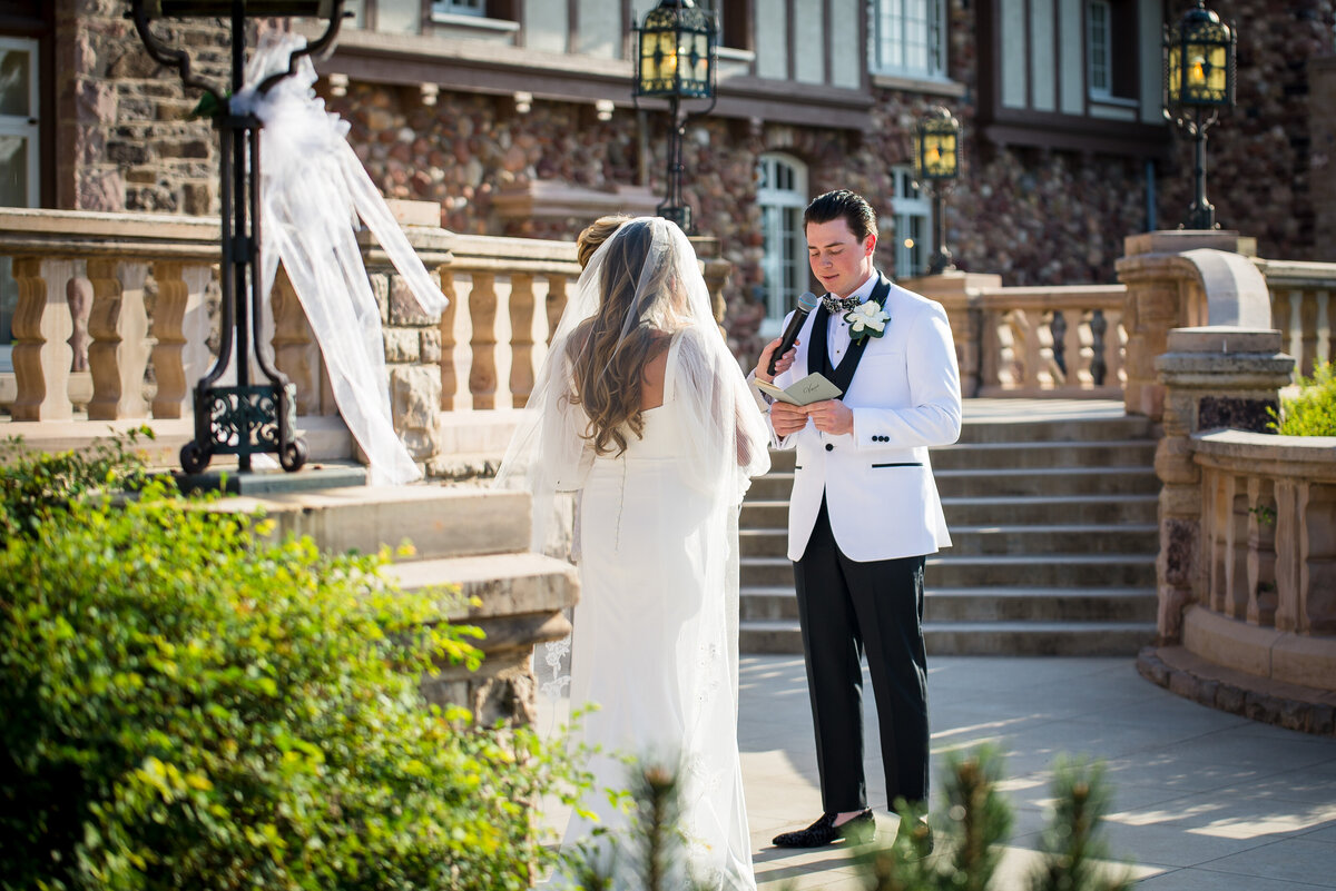 A groom reads his private vows to his bride on the steps of The Highland Ranch Mansion in Colorado.