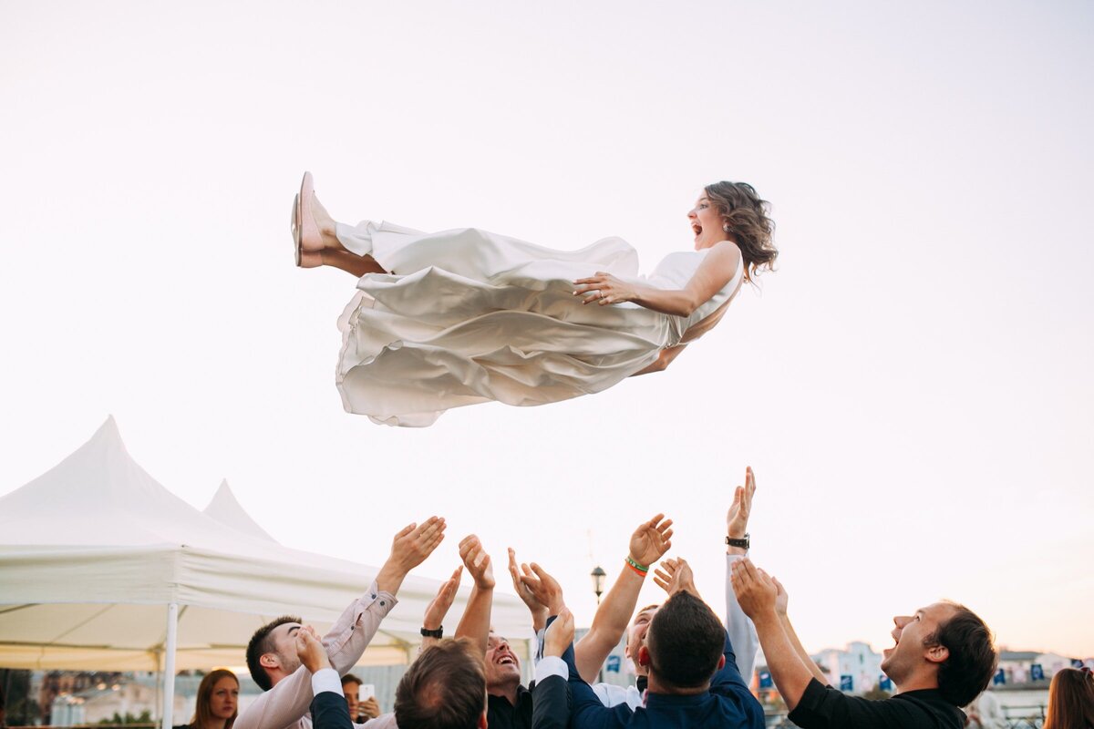 Bride being tossed in the air by wedding party