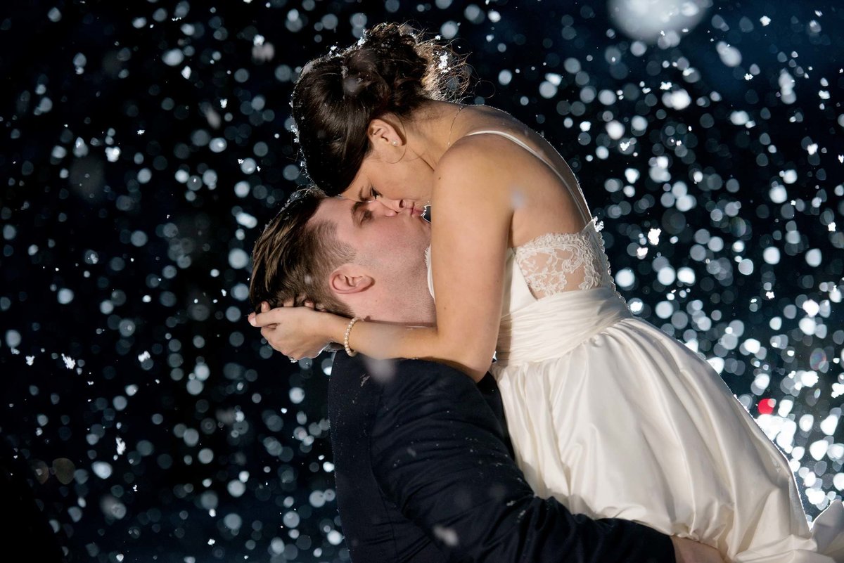 Bride and groom kissing outside in a snow shower at The Mansion at Oyster Bay