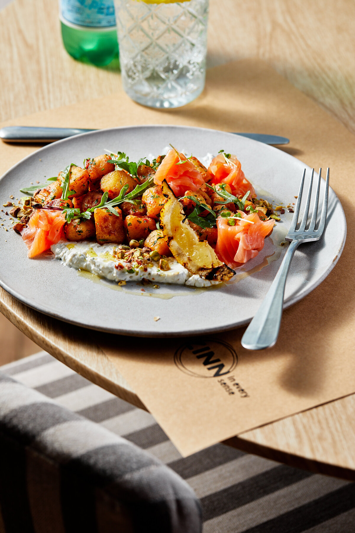 A plate of labneh topped with spiced fried potatoes and smoked salmon.