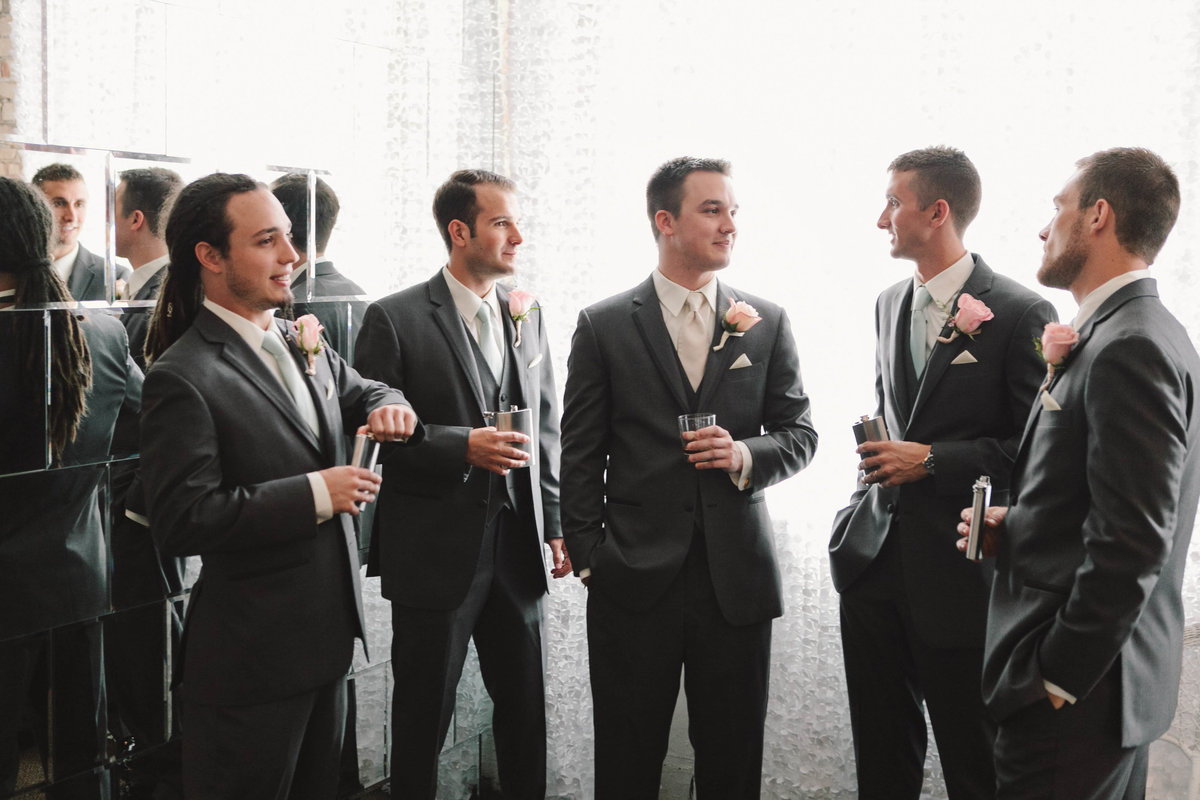 Groomsmen talk while holding whiskey drinks at The Allure wedding in La Porte Indiana