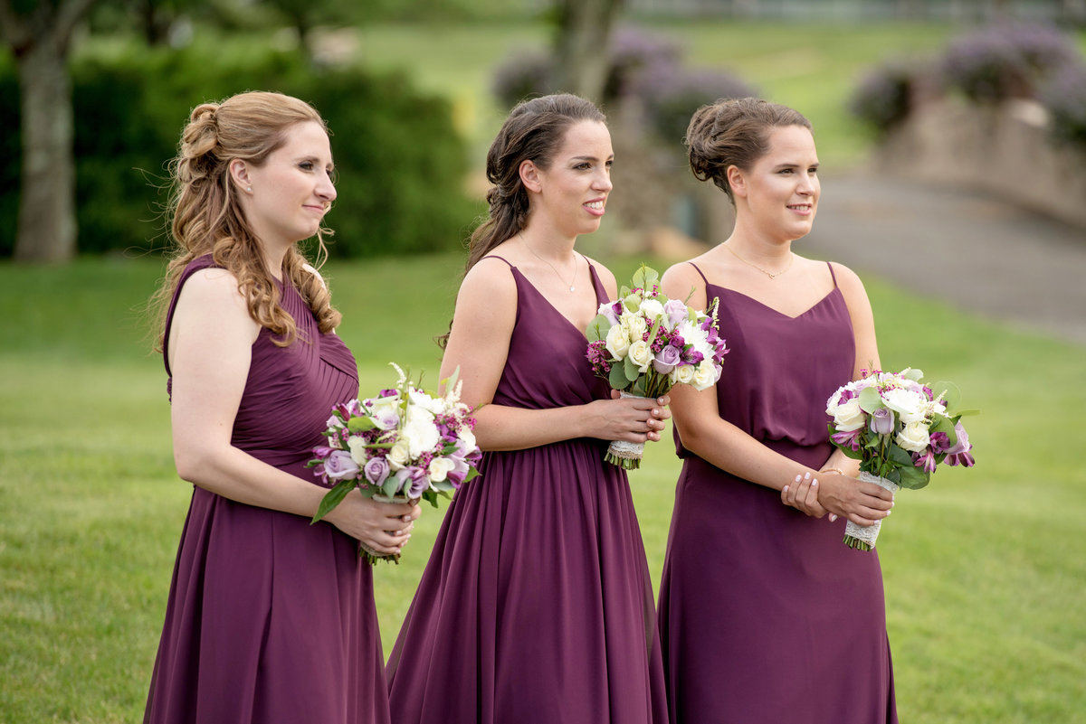 bridesmaids in burgundy during wedding ceremony on the golf course at Willow Creek Golf and Country Club