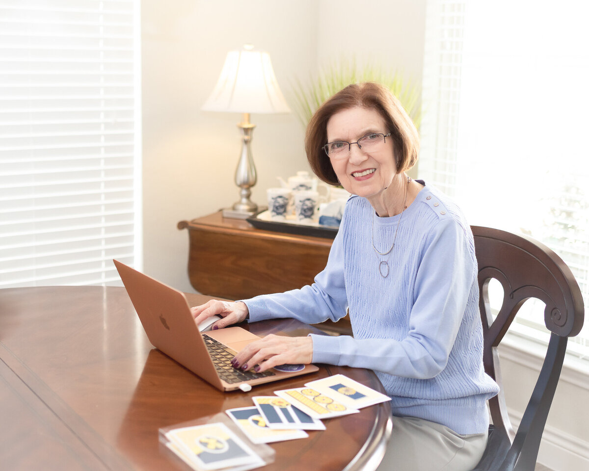 business owner in purple sweater working on her laptop smiling for camera