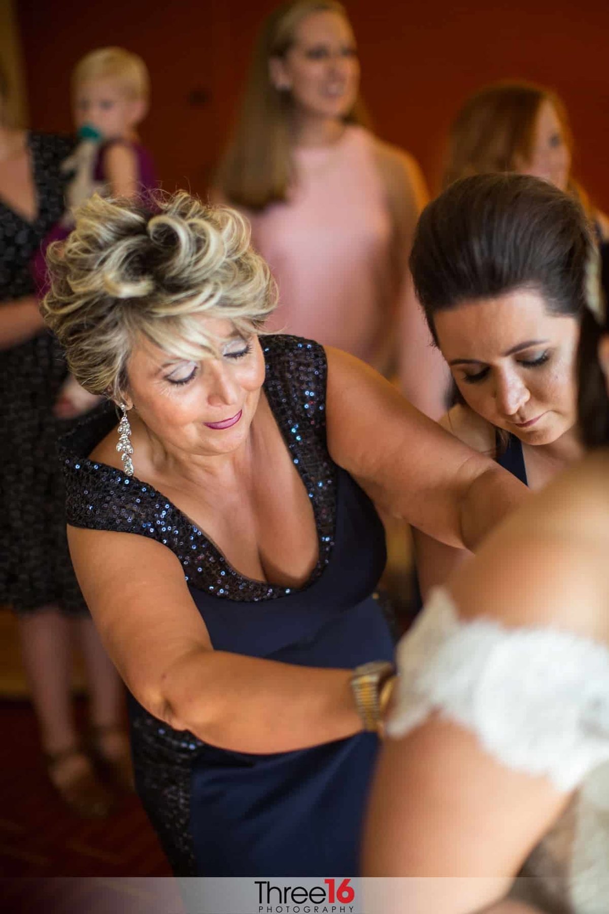Mother buttons up Bride's dress