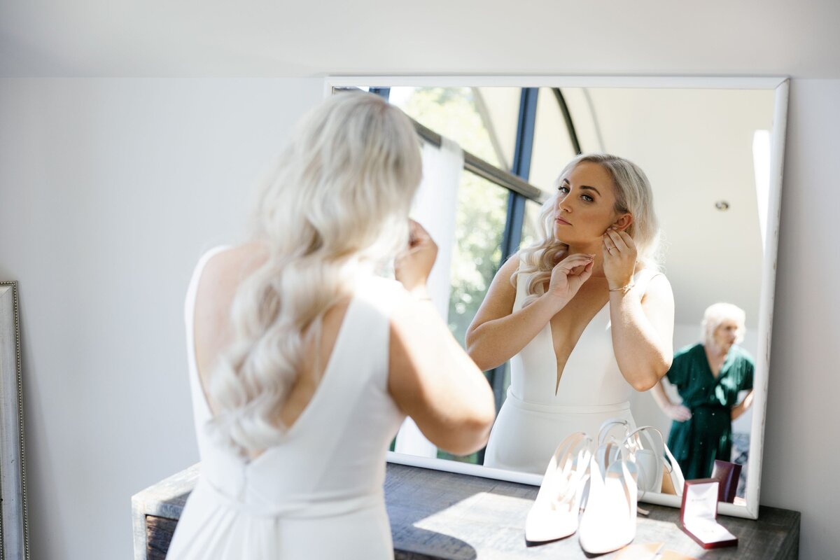 Bride with Glamour waves and smokey golden eyeshadow looking in mirror