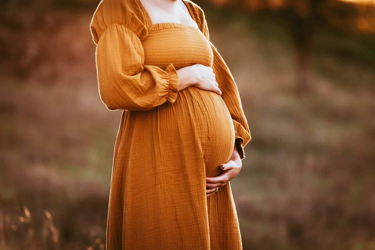 Pregnant mama in orange dress holding her belly