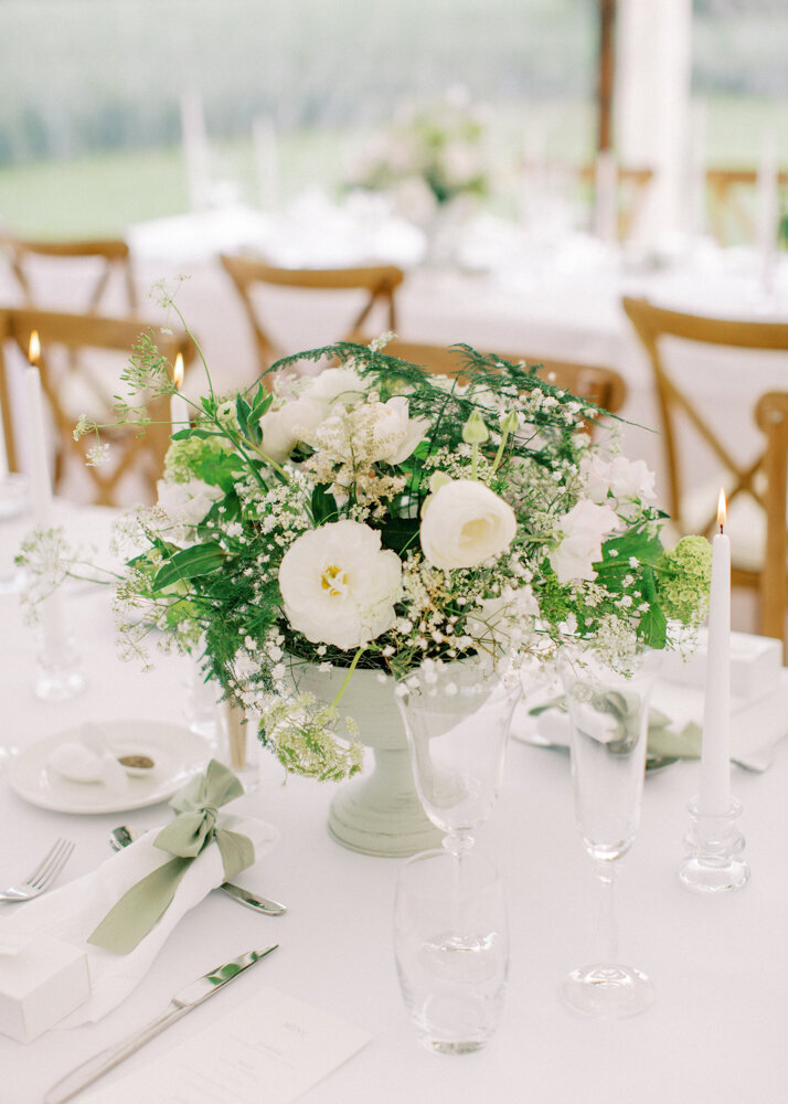 wedding table setting with white tall lit candles in the crystal candle holders and white roses arrangement centrepieces