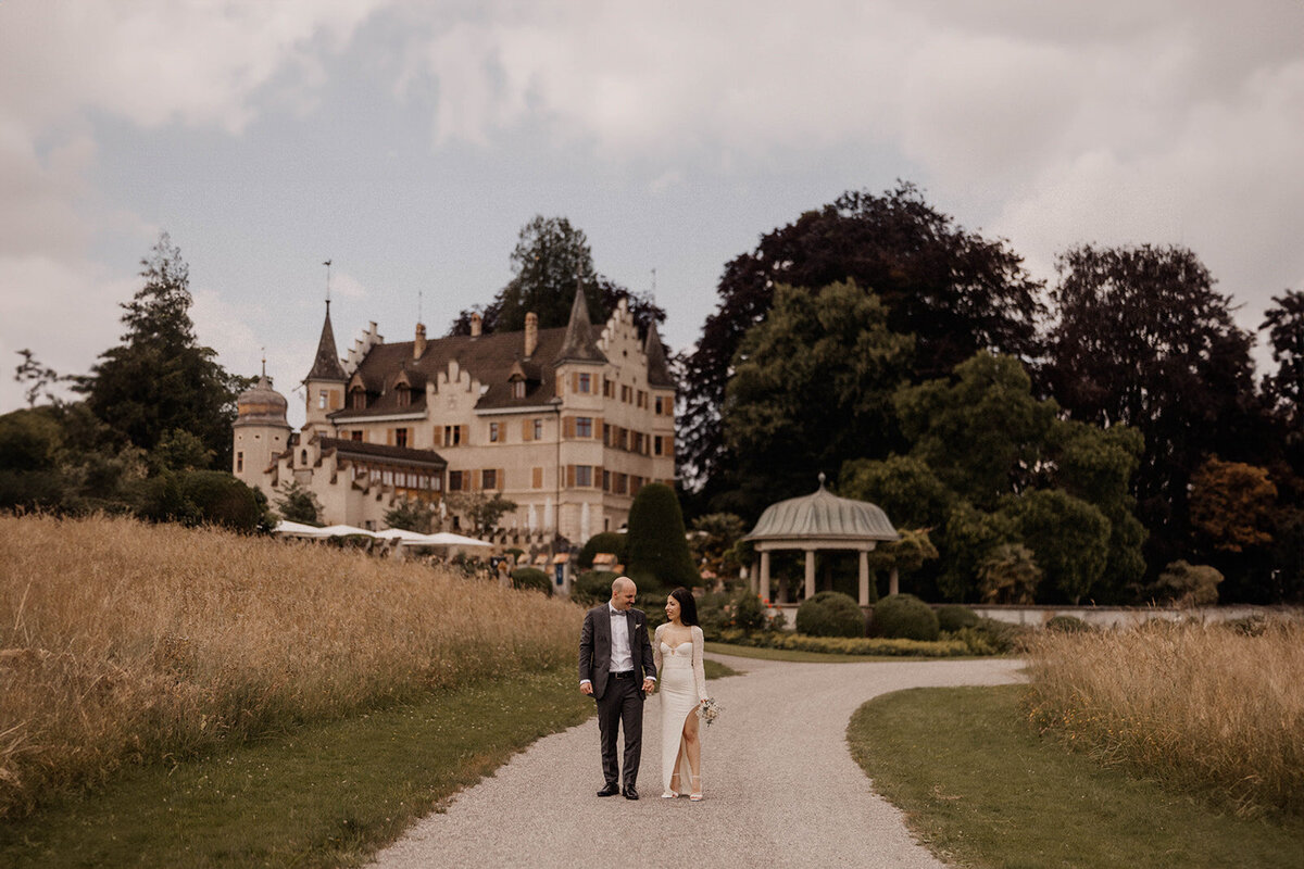 Brautpaar spaziert vor Schloss Seeburg in Kreuzlingen – Hochzeitsfotos mit Schlossflair


