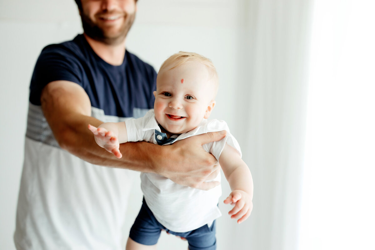 baby boy playing with dad in the air for family photos