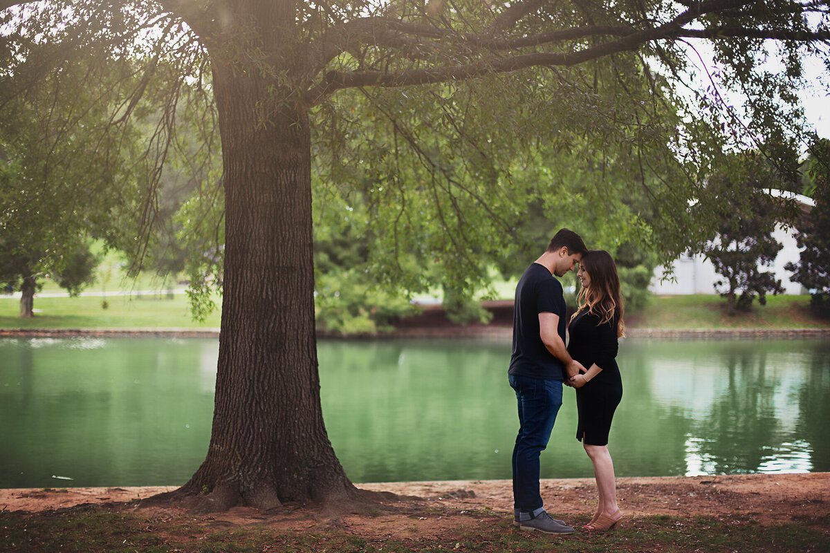 pregnant couple standing in front of pond freedom park charlotte