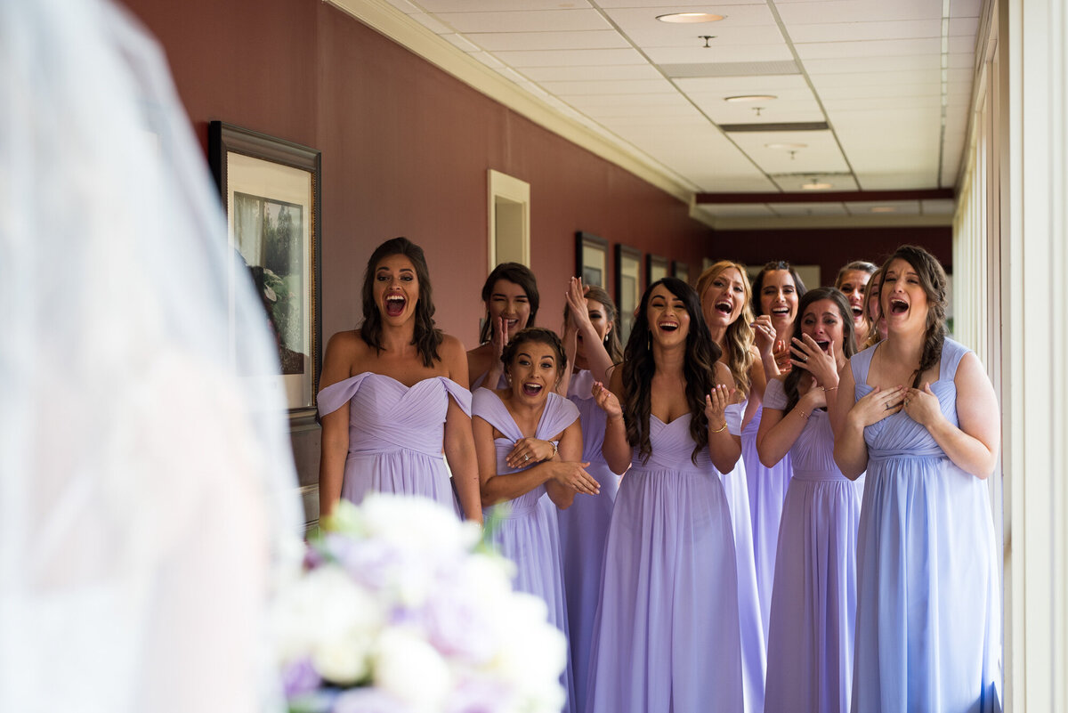 Bridesmaids cheer as they see their friend in her wedding dress for the first time