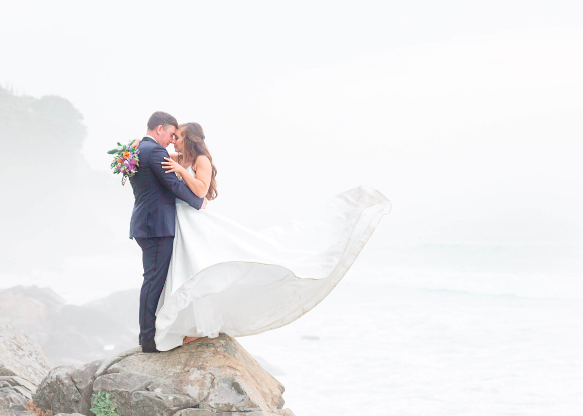 adventurous bride and groom standing on rocks at York Harbor beach for york Inn Wedding  (17)