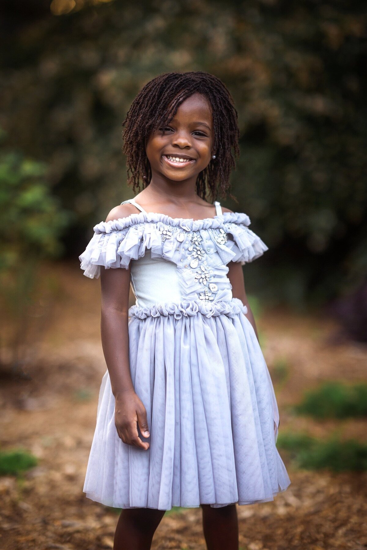Young girl in dress is smiling at the camera at her photosession.