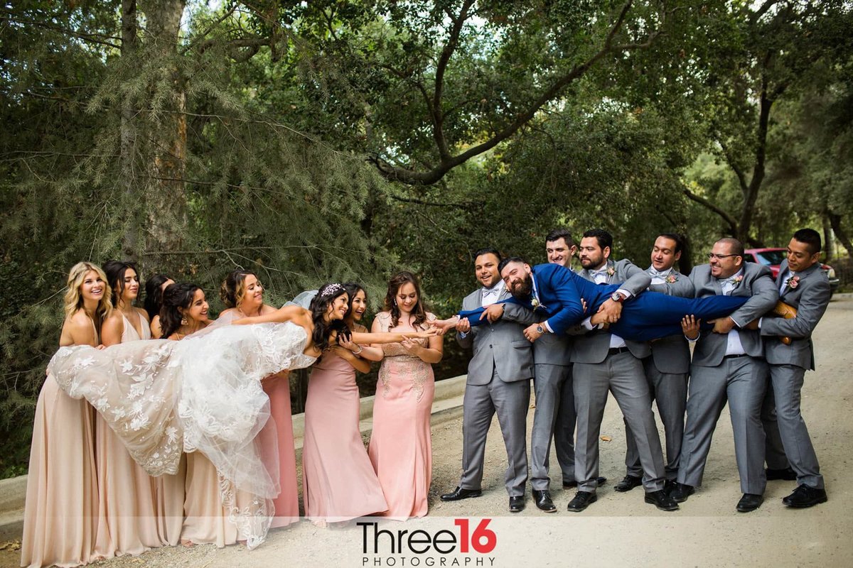 Bride and Groom reach out for each other while in the arms of the Bridal Party