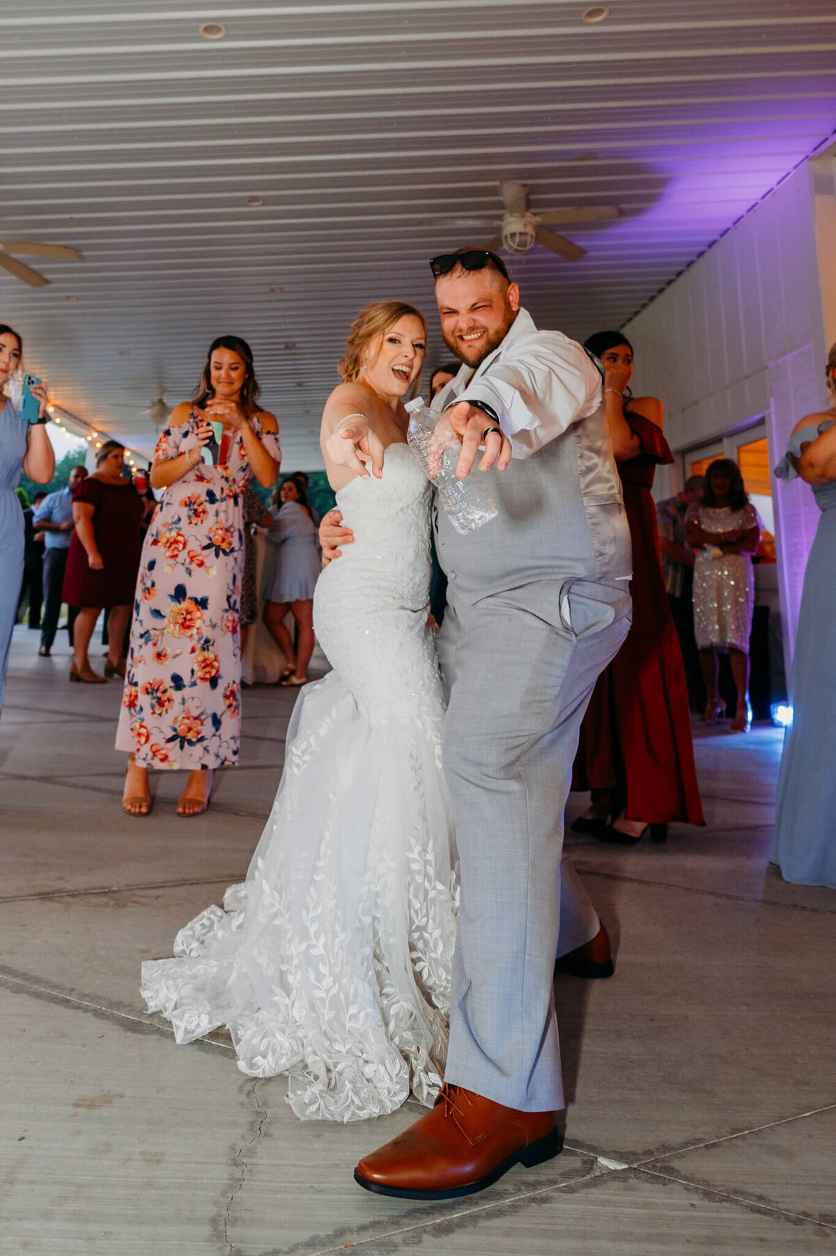 A photo of a bride and groom dancing and pointing at the camera wearing their wedding reception