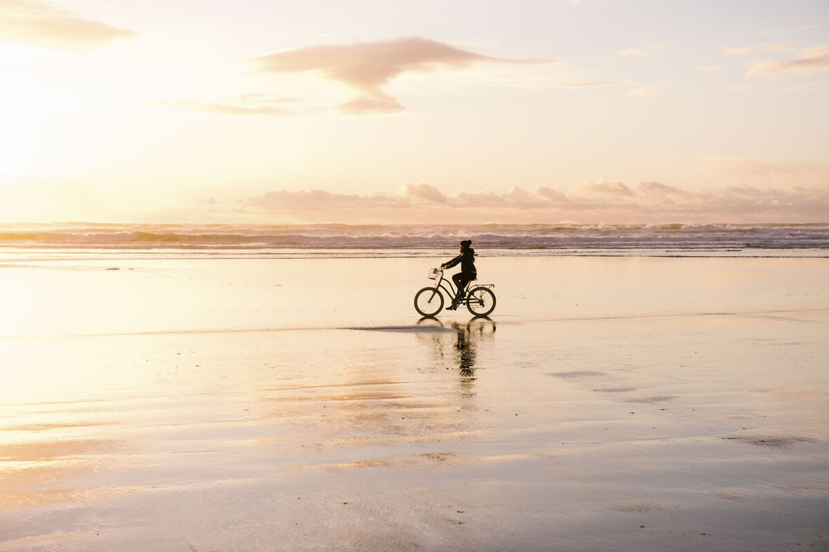 Single cyclist on beach at sunset