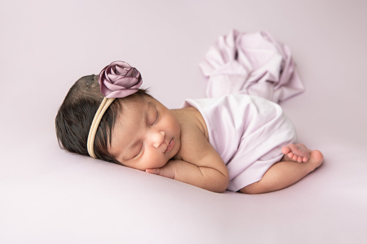 Posed newborn on a lilac backdrop