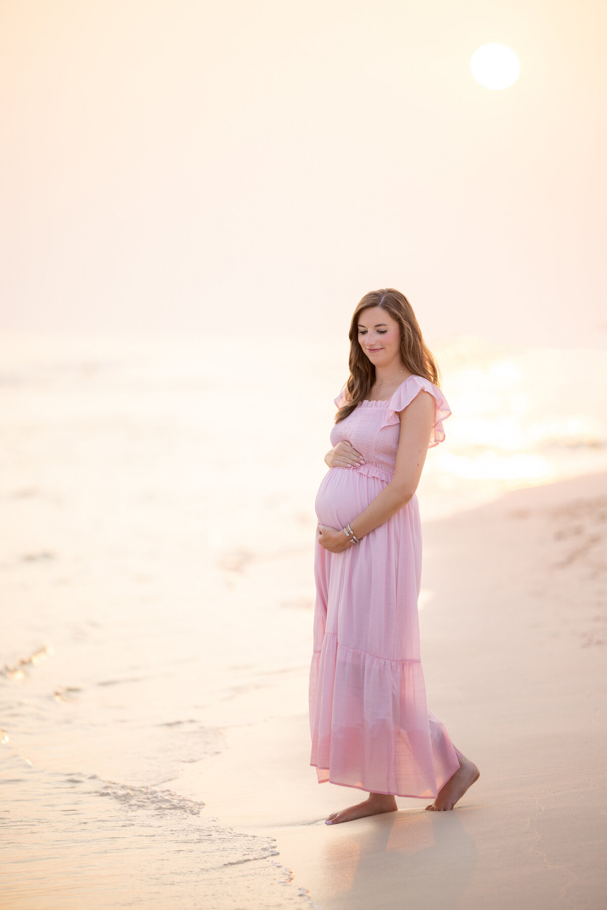 A pregnant woman walking along the water's edge in Inlet Beach.