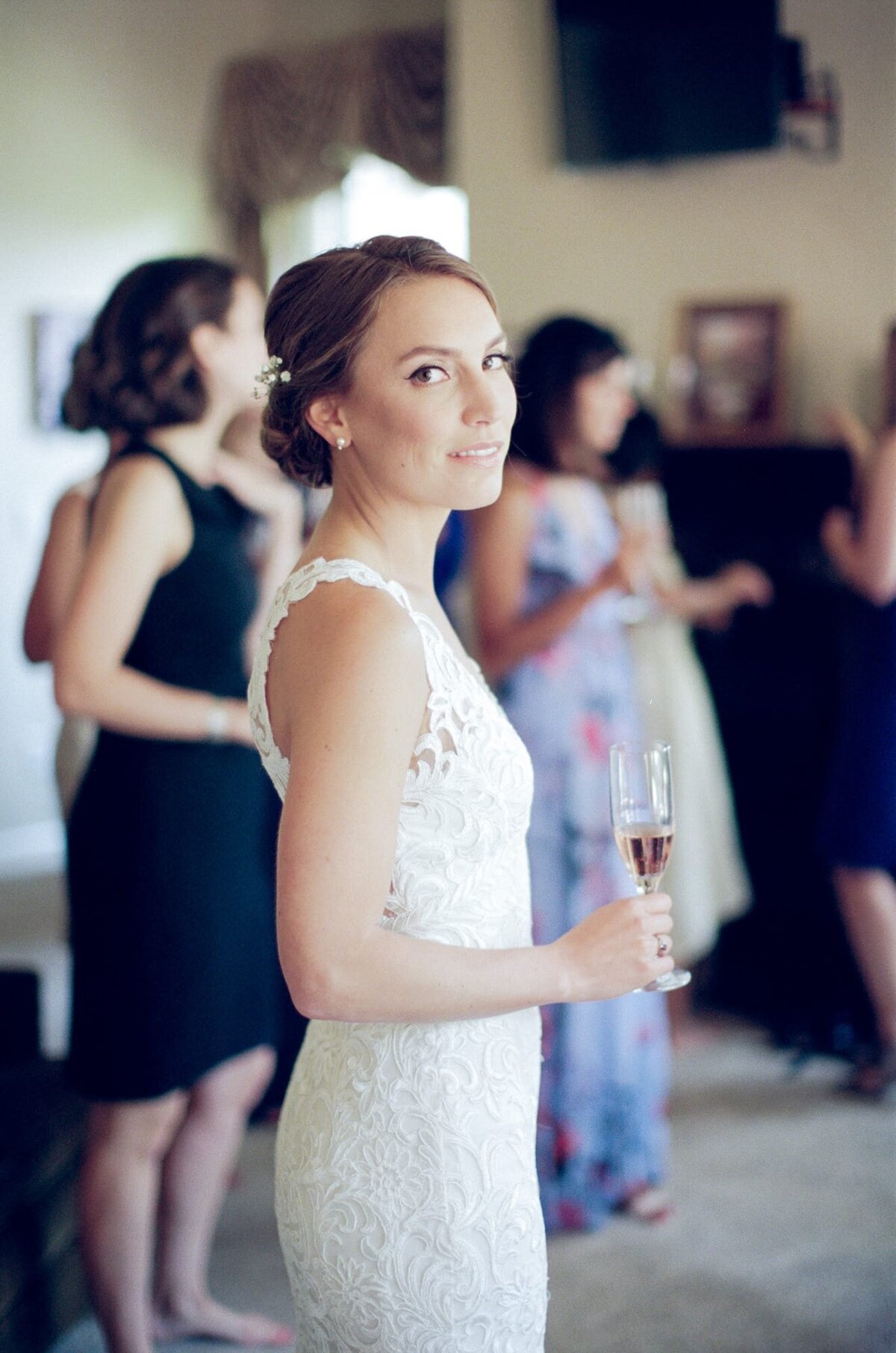 Side-angle capture of a beautiful wedding bride holding a drink and looking at the camera.