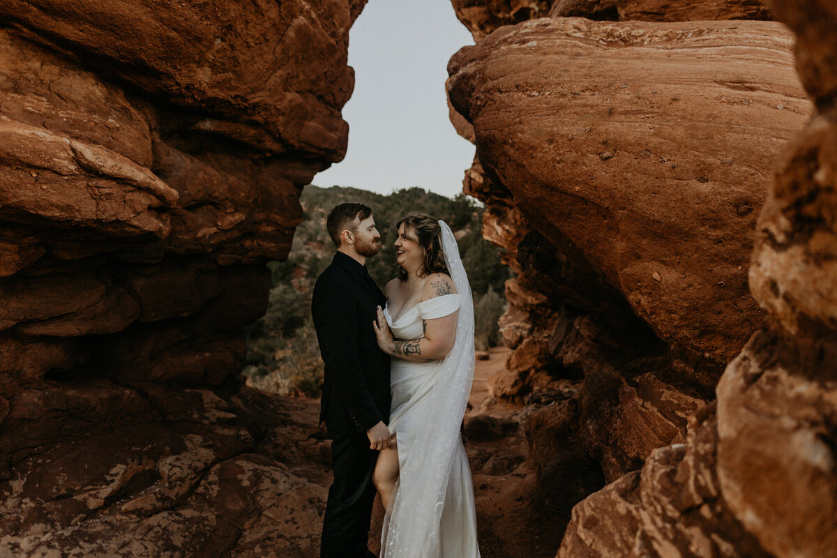 newlyweds standing between red rocks at Garden of the Gods in Colorado
