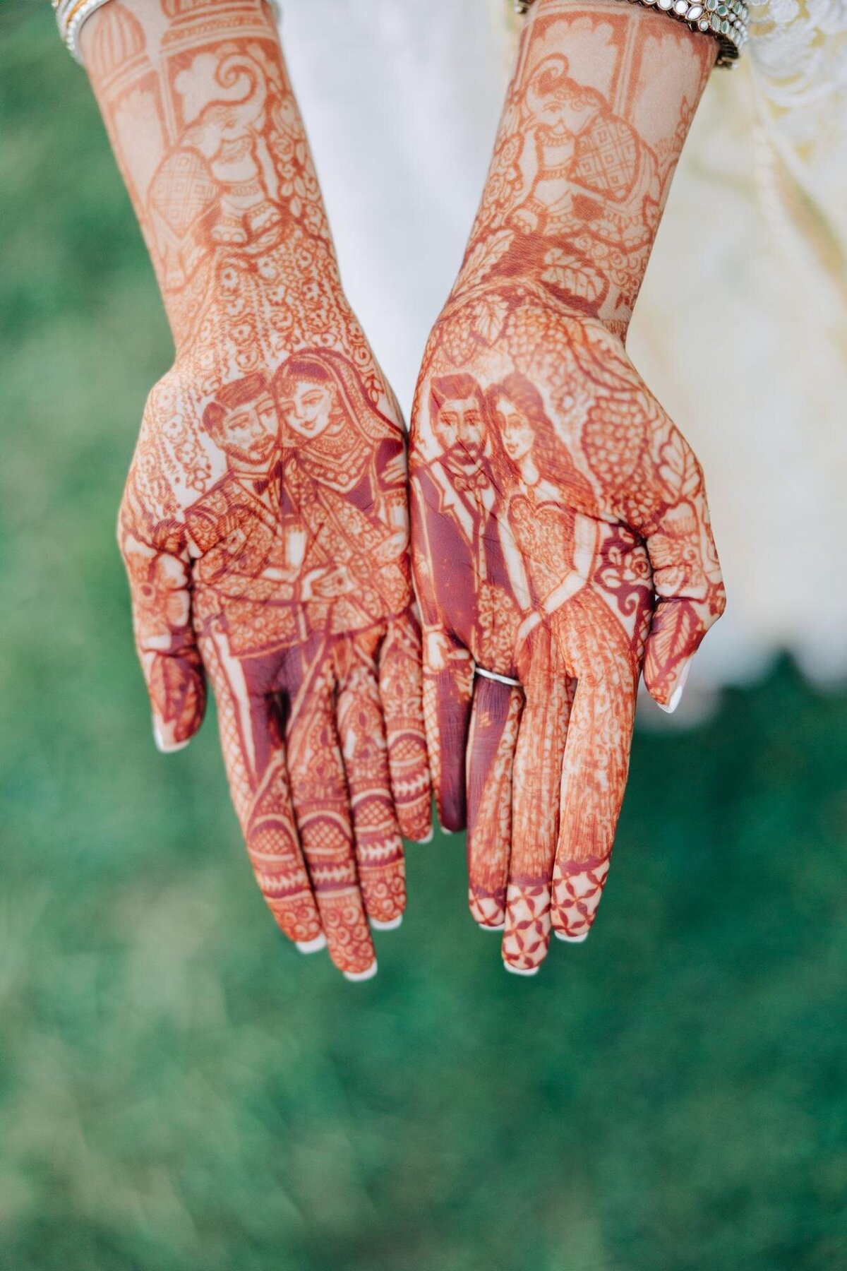 A person showcasing intricate henna designs on their hands, including a depiction of a couple.